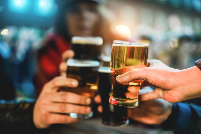 Young group of people having fun cheering with beer outdoor at bar restaurant