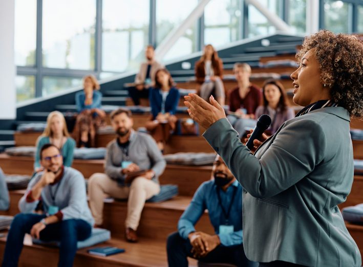 Female speaker talking on a business conference at convention center.