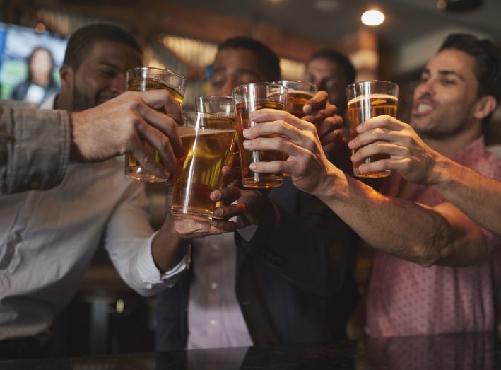 Group Of Male Friends On Night Out For Bachelor Party In Bar Making Toast Together