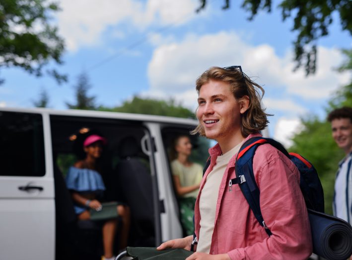 Multiracial young friends travelling together by car - summer vacation, holidays, travel and road