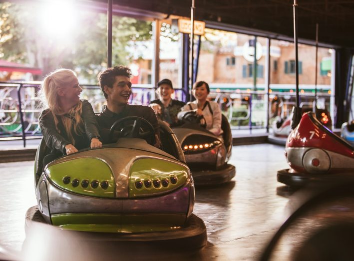 Young people driving bumper car at amusement park